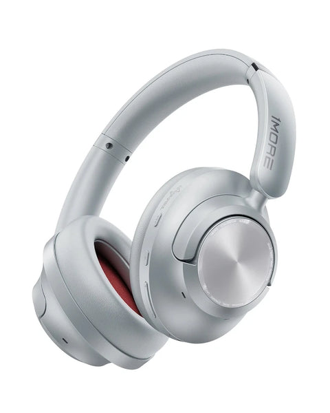 Silver over-ear wireless headphones with a metallic circular dial on the ear cup and a red inner ear pad, shown on a plain white background. The brand name 'iMORE' is visible on the headband.
